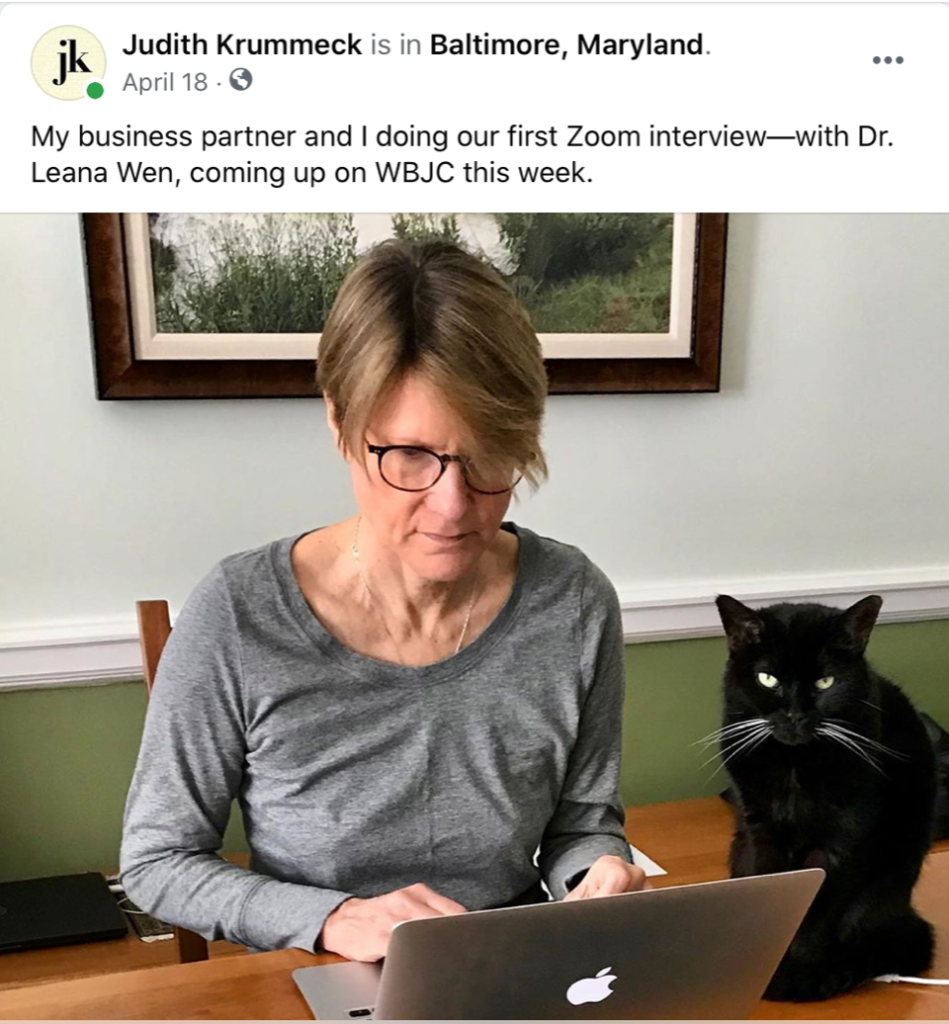 Facebook post reads: "My business partner and I doing our first Zoom interview—with Dr. Leana Wen, coming up on WBJC this week." Krummeck pictured at computer with her cat.